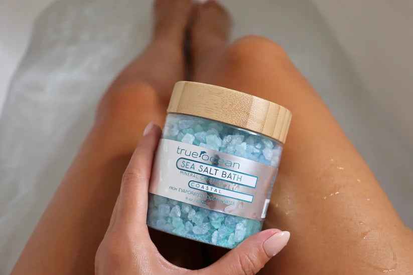 Person holding a jar of True Ferrosan Sea Salt Bath in a bathtub.