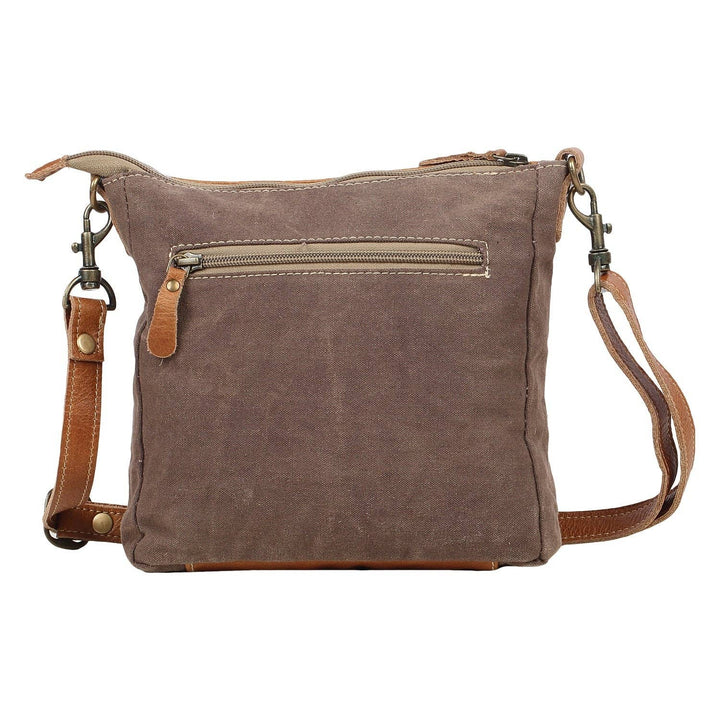 Brown leather crossbody bag with a strap on a white background