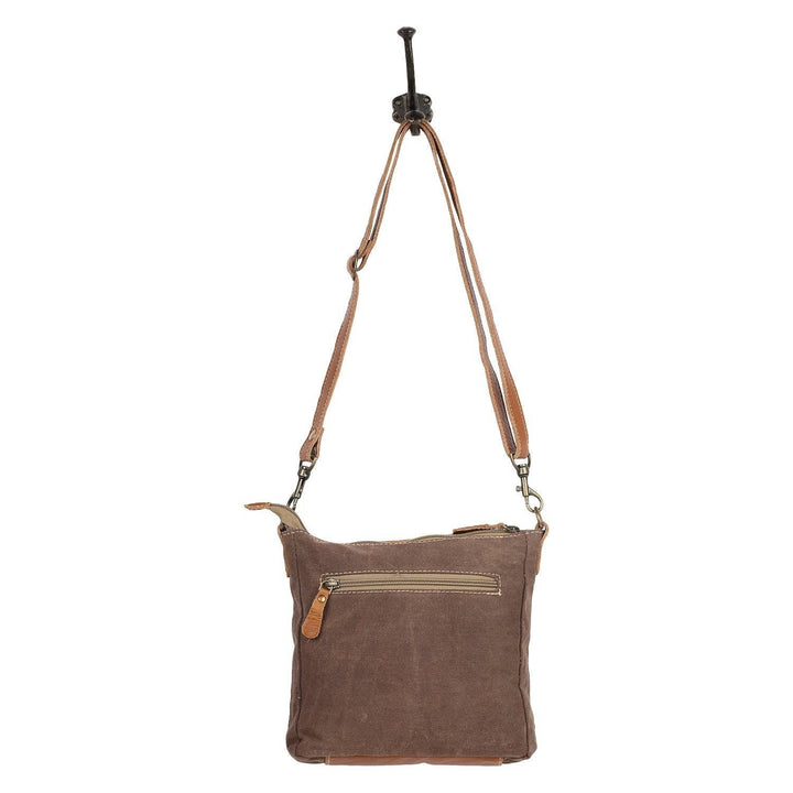 Brown suede crossbody bag with leather strap on a white background